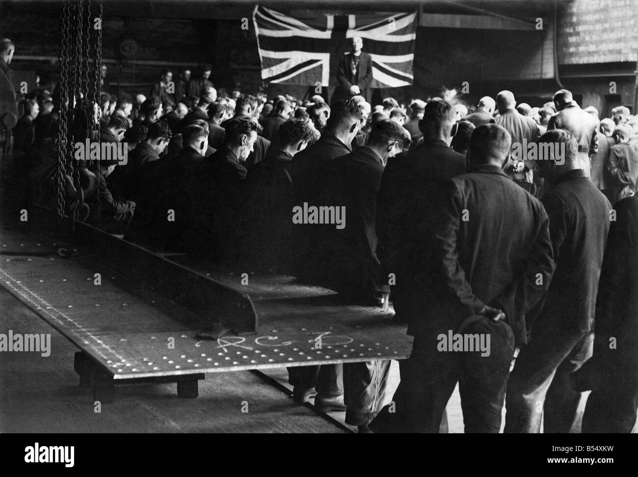 World War II Religion. Lunchtime prayer in the shipyard. So that there would be no interference with production the National Prayer Service in a N. East Shipyard was held during the lunchtime break. Hundreds of men stood with their heads bowed, following the Bishop of Durham, Dr. Alwyn. Williams as he said the Lord's Prayer. The short simple service lasted ten minutes, and as the whistle blow to recommence work, once again the stillness was broken by the hammering of rivets, and the clanging of steel plates, which will go down to the sea in ships to fight for freedom....September 1942 P011612 Stock Photo