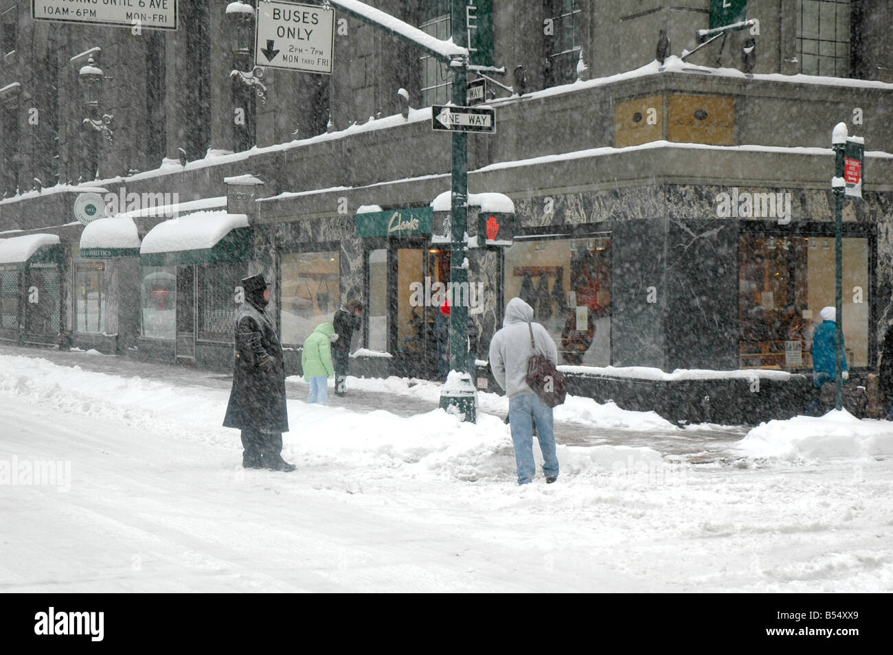 doorman and hotel guest stand on empty street corner of madison avenue during a winter storm Stock Photo