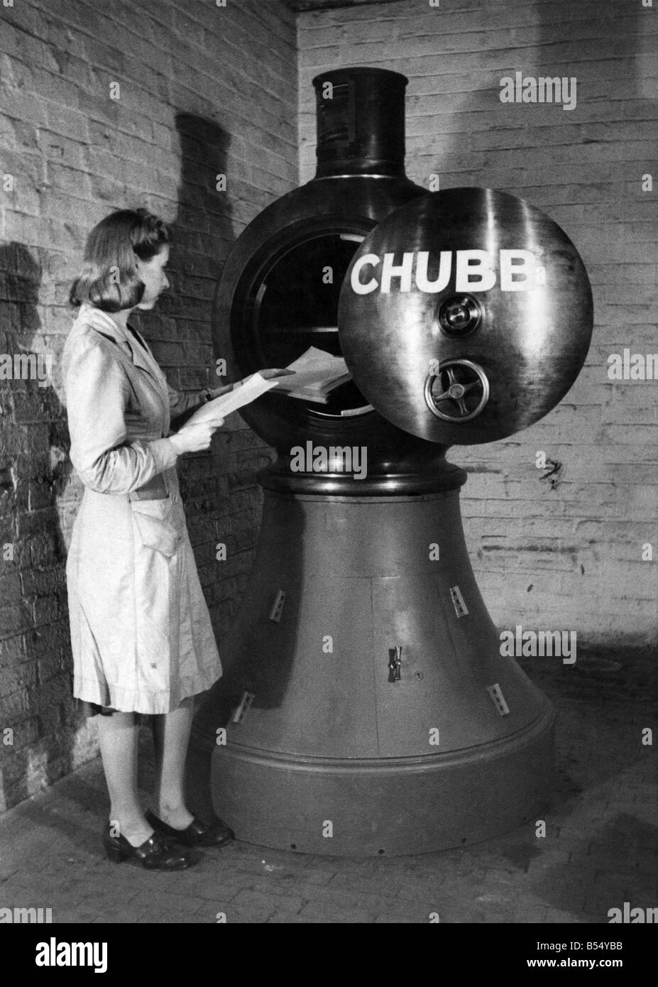 The 2 1/2 ton Revolving Lighthouse Safe. Here a woman is seen placing papers in the lighthouse. She is also locking it. The light at the top flashes like a lighthouse and revolves with the iron safe. This is worked by a motor underneath. Any attempt by burglars to stop the safe revolving immediately puts out the light and rings alarm gongs. While the light is still flashing police know that all is safe. There has been only one model of the Revolving Lighthouse Safe made by Chubbs, Ltd. of Wolverhampton. Mr. Edward Chubb said he did not think any more Lighthouses would be made. May 1944 P012172 Stock Photo