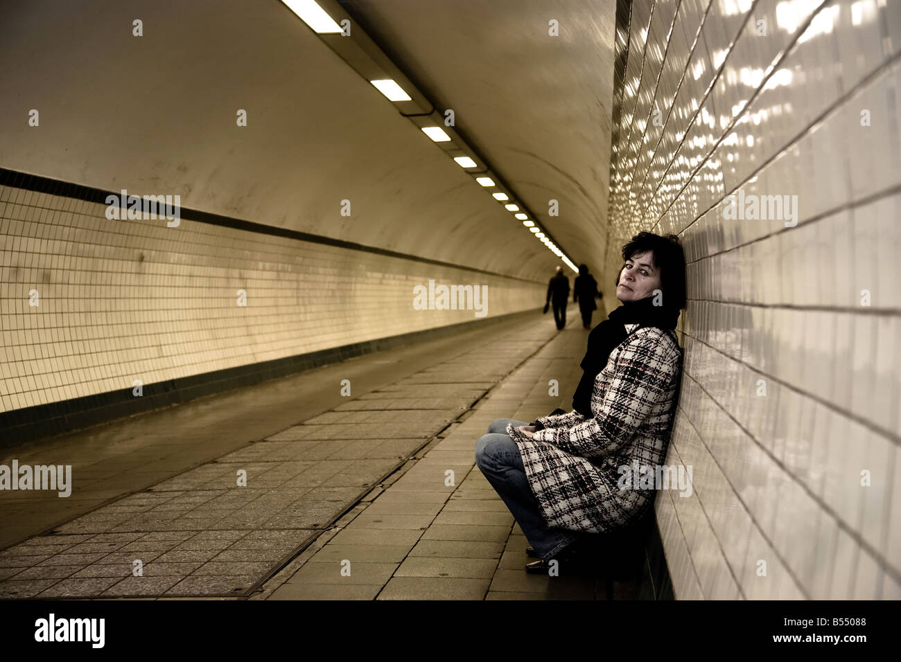 sad mature woman in a tunnel two business people in the background ...