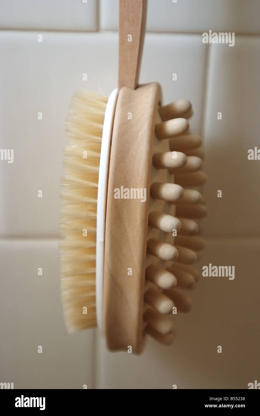 Bath brush hanging on a white tile shower wall Stock Photo