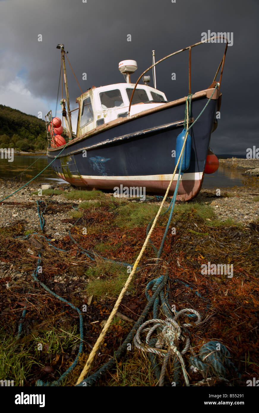 blue and white fishing boat moored in a bay with the tide out in the ...