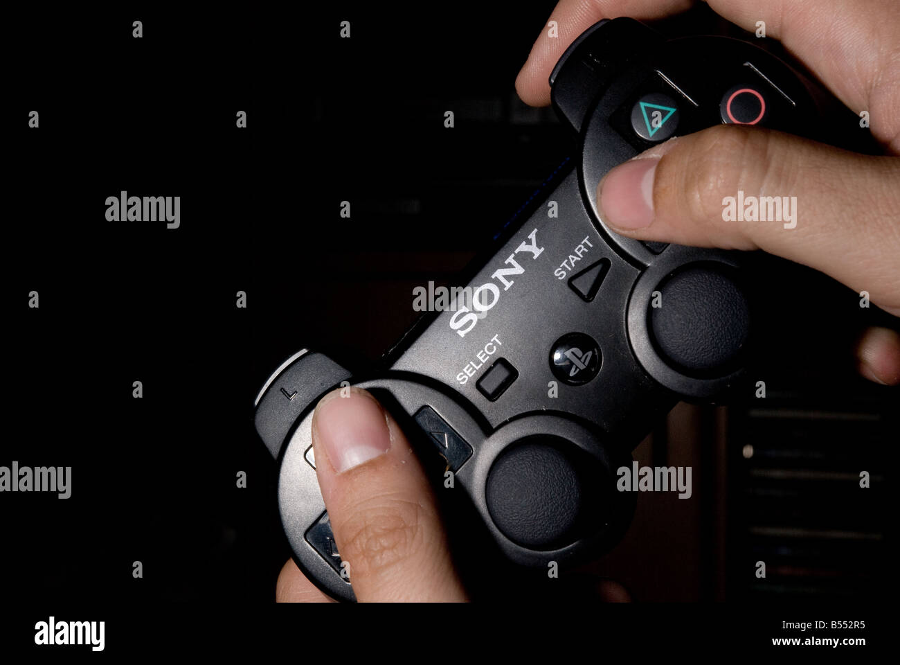 A Sony Playstation 3 controller being used to play a game. Stock Photo