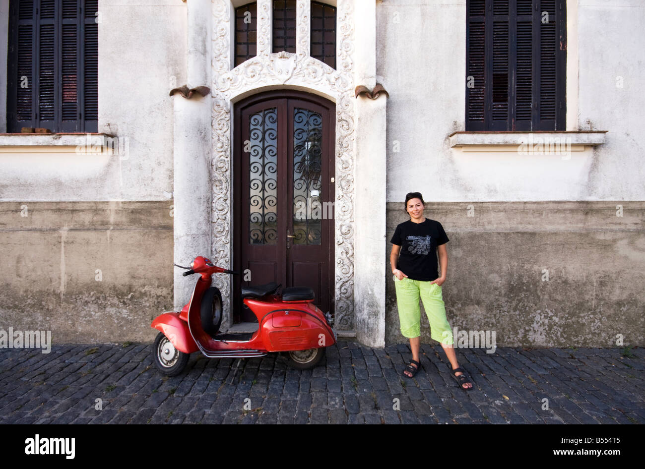 A young woman poses for a photo next to a red vespa in Colonia del Sacramento Uruguay Stock Photo