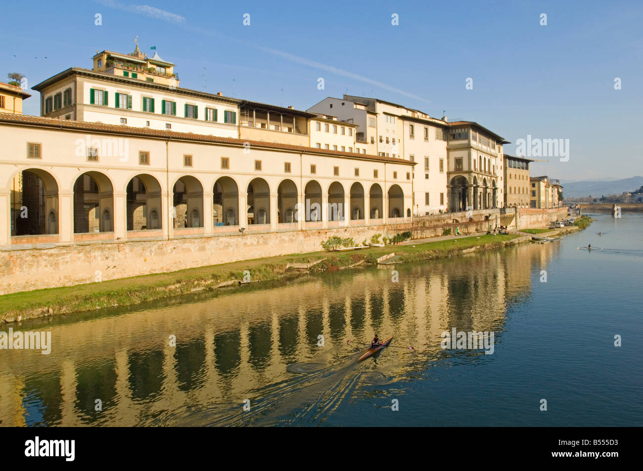 A rower on the Arno river going past the Uffizi along Lungarno Generale Diaz with the Vasari corridor above the arches. Stock Photo