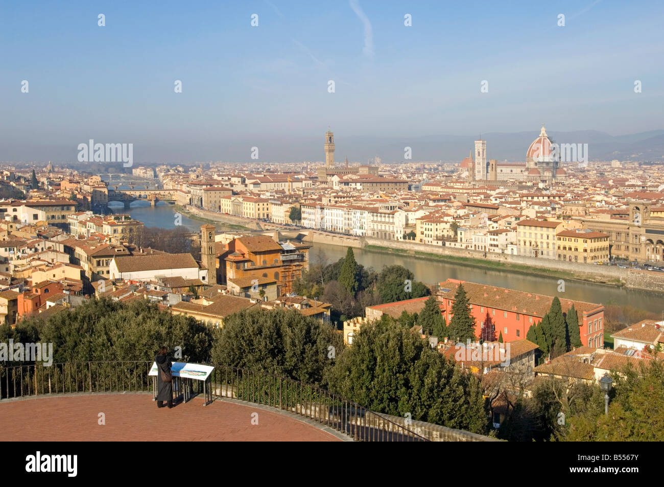 A wide cityscape view of Florence with a tourist in the forground at the Piazzale Michelangelo viewing area. Stock Photo