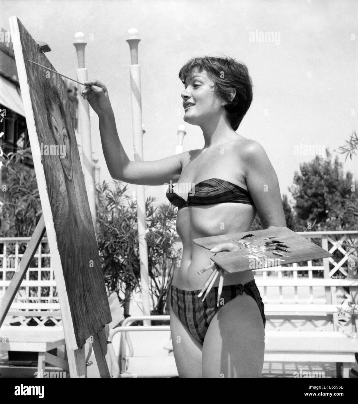 Venice Film Festival 1953. Novella Pariginia who has come to the festival to paint the visitors. She believes in comfort and wears a bikini when painting. She is seen here paint us actress Lya Haby. August 1953 D5369-021 Stock Photo