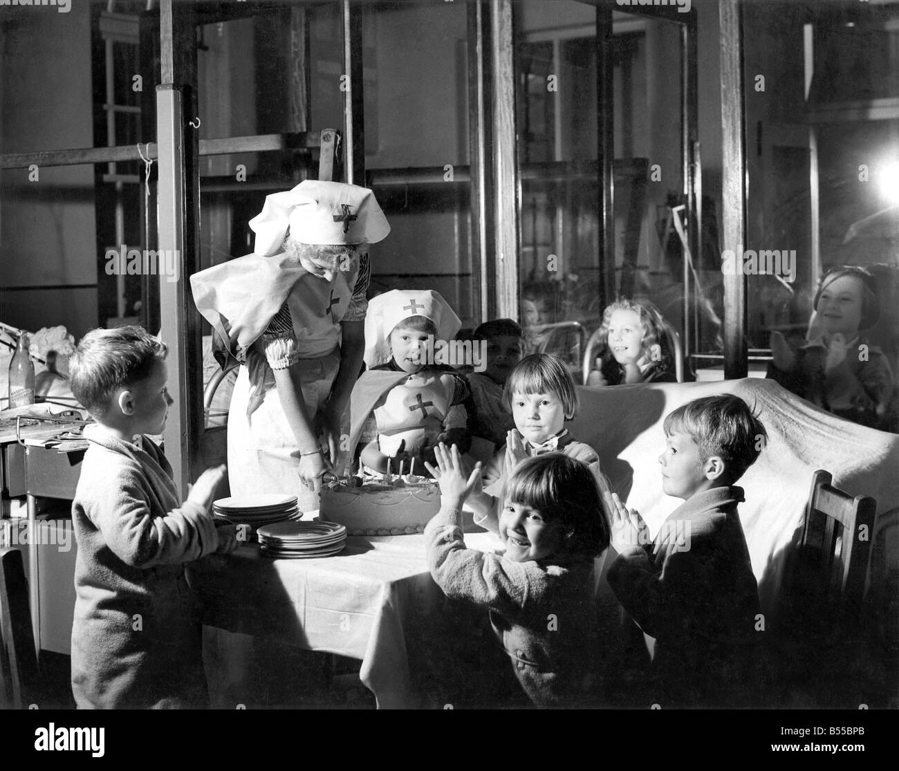 Elizabeth (8) and Christine (5) Sainsbury of Nutley, Plymouth, shared the birthday with children in a ward at City Hospital, Plymouth, today. Accompanied by mummy, the sisters whose birthdays fall together today, each had a nurse's uniform to wear. November 1951 P013705 Stock Photo