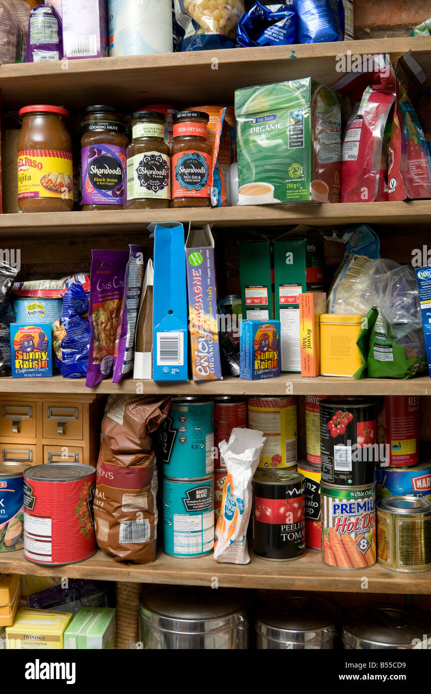 wooden kitchen shelves loaded with cans and jars and packets of  basic staple ordinary foods for family meals for a week, UK Stock Photo