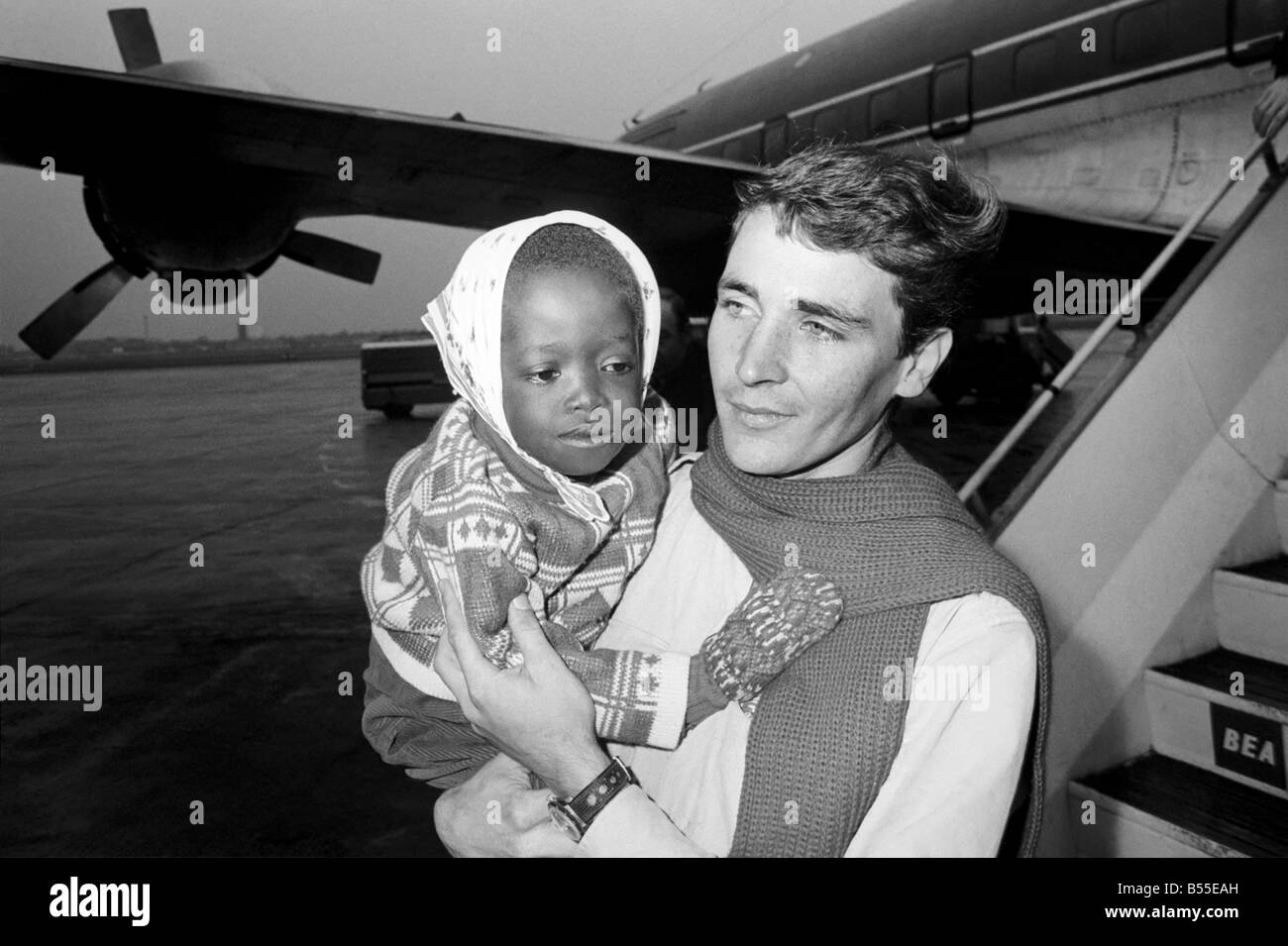 Five sick biafran children who have fled their war torn home arrived in London Yesterday (Fri) on a Mercy Flight from ULI. Their aircraft left the airstrip only minutes after a bombing raid on Wednesday. The two teenaged girls, two boys aged 10 and five and an 18 months old baby girl will be cared for in hospitals in England and Ireland. Cyrina Eleebe (held by man), who is going on to Germany. December 1969 Z12284-004 Stock Photo