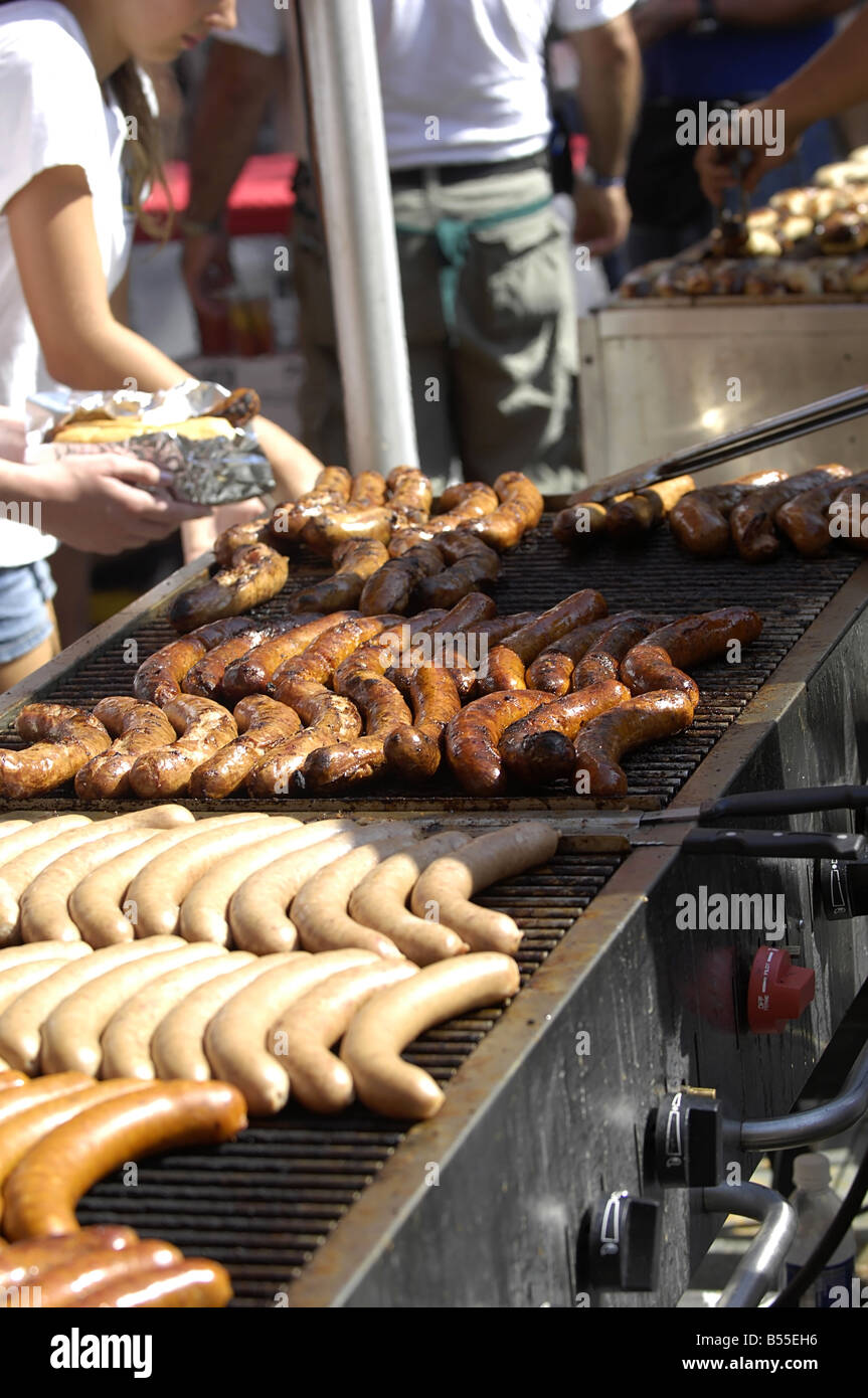 Sausages Hot Dogs and Wieners being grilled on a large outdoor barbecue