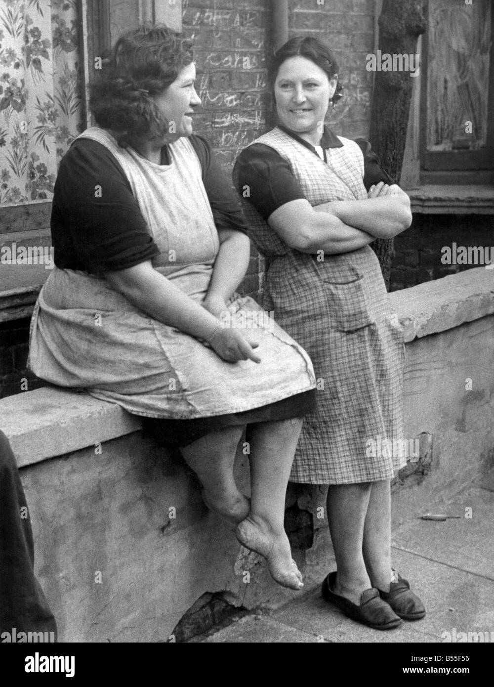 Women. Dock Strike. On the left is Mrs. Demmon, her husband was a Docker, now abroad in the army. She has eight children. She, like several other women seen in the district, goes about barefooted so that they can purchase footwear for their children. Seen talking to Mrs. Mary Reading, a Docker’s wife, who has to budget for ten. She also is wearing make-do footwear. Taken outside their homes in Chauntler Road, Victoria Docks. October 1945 P009035 Stock Photo