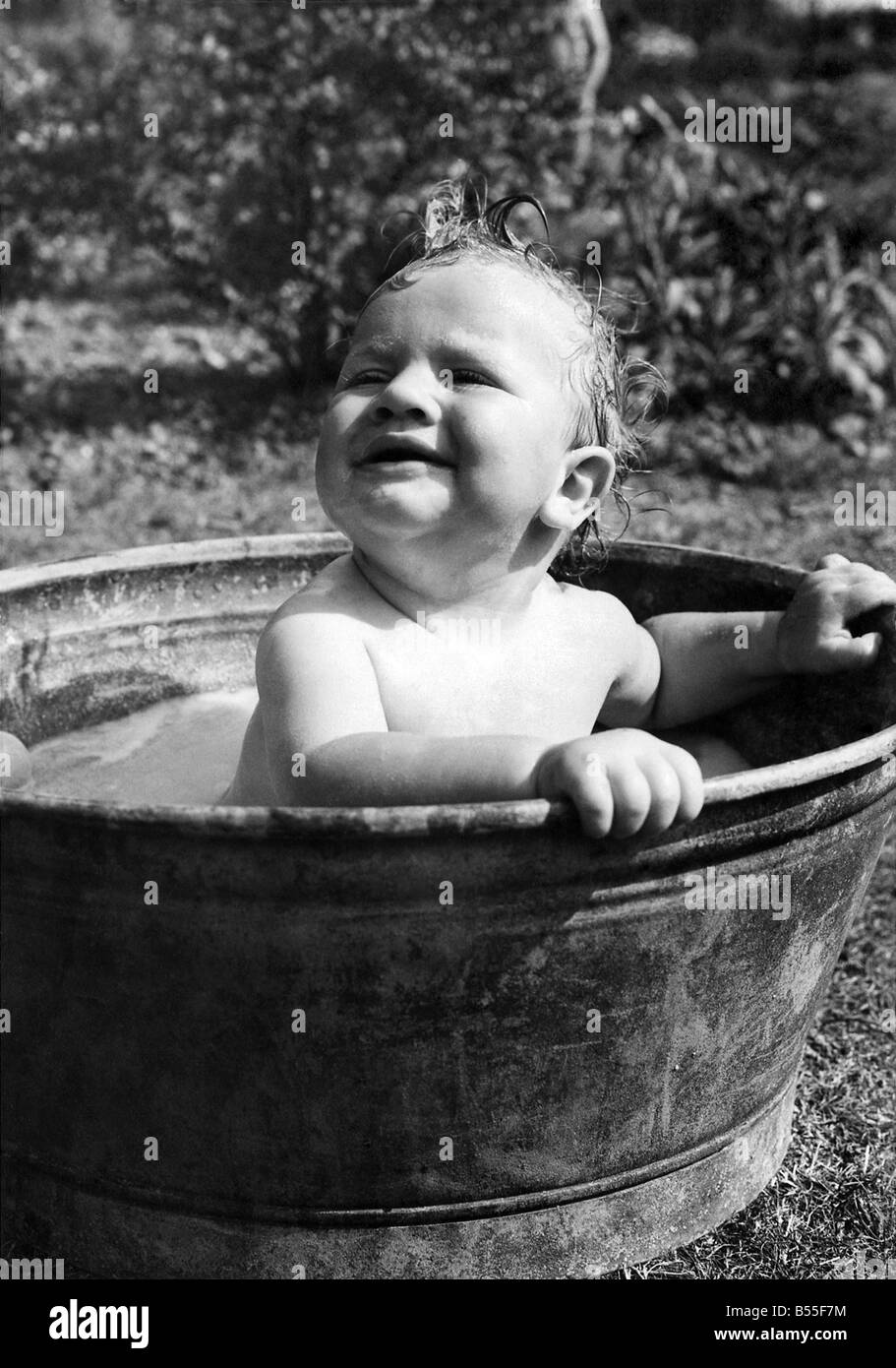 Young toddler having a wash in a tin bath in the back garden in Erith