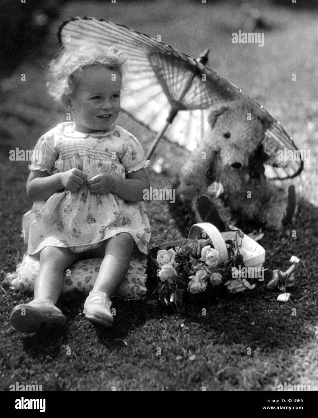 Young girl sitting in her back garden shading her teddy bear from the ...