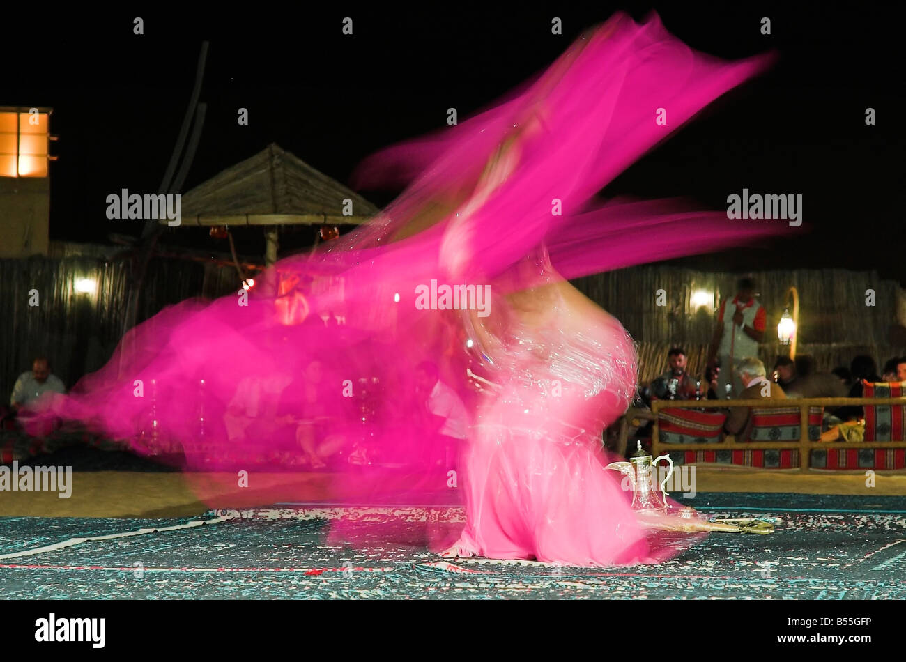 Belly dancer twirling on carpet in desert in Dubai Desert Conservation Reserve Stock Photo
