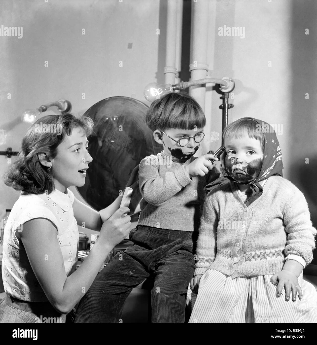 Joe, 4, and Tessa 2, play with tyhe grease paint as their mother Helena Hughes, (Mrs. Helena Gannon) aged 24, London born actre Stock Photo