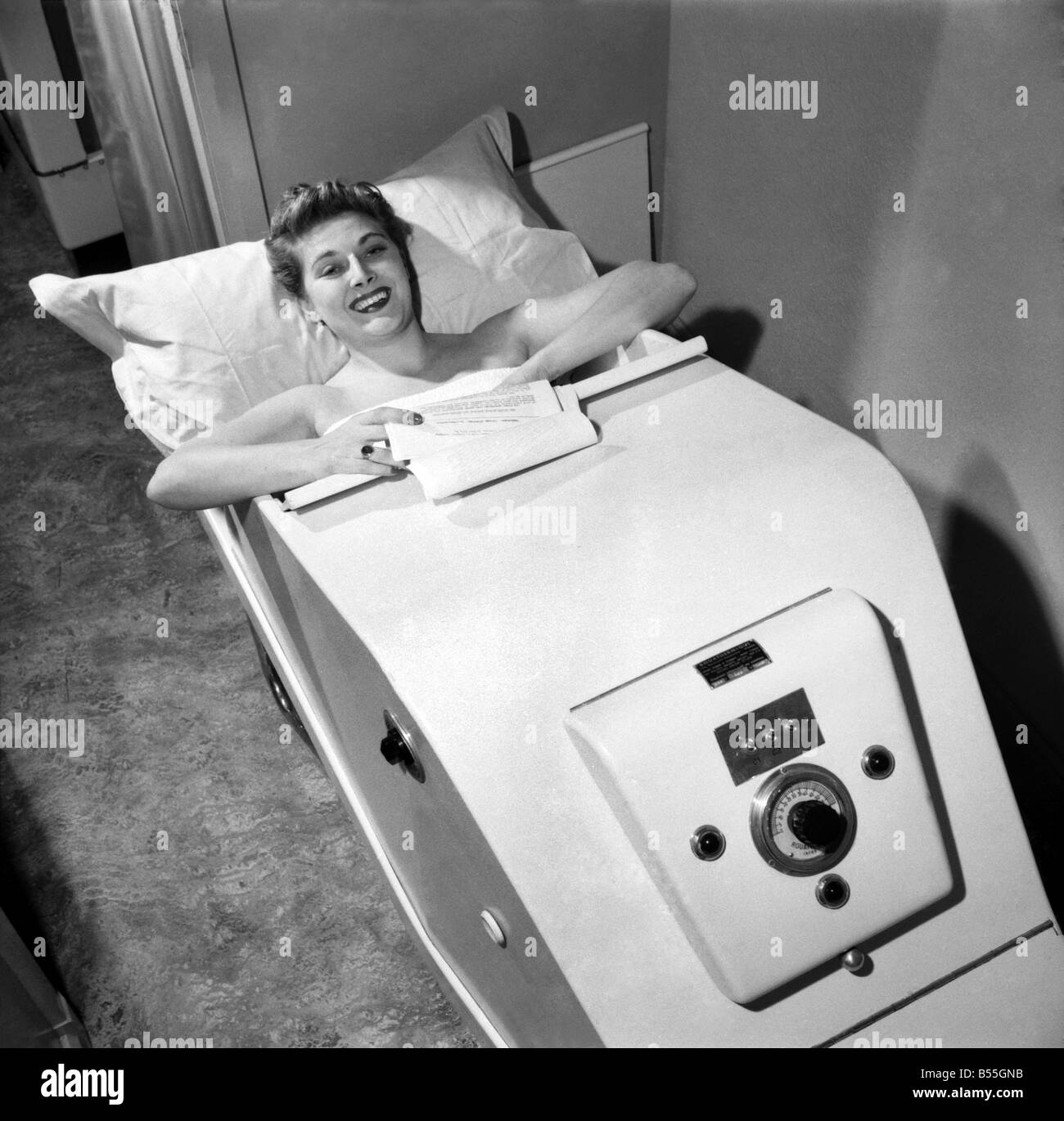 Actress Hy Hazel relaxes as she studies her part as Principal Boy in the Puss in Boots panto at the Manchester Palace in a new dry heat rheumatic bath. This bath, imported from Paris for the openign of a new beauty clinic in Manchester, is a refresher for the nervously exhausted. December 1953 ;D7370-001 Stock Photo