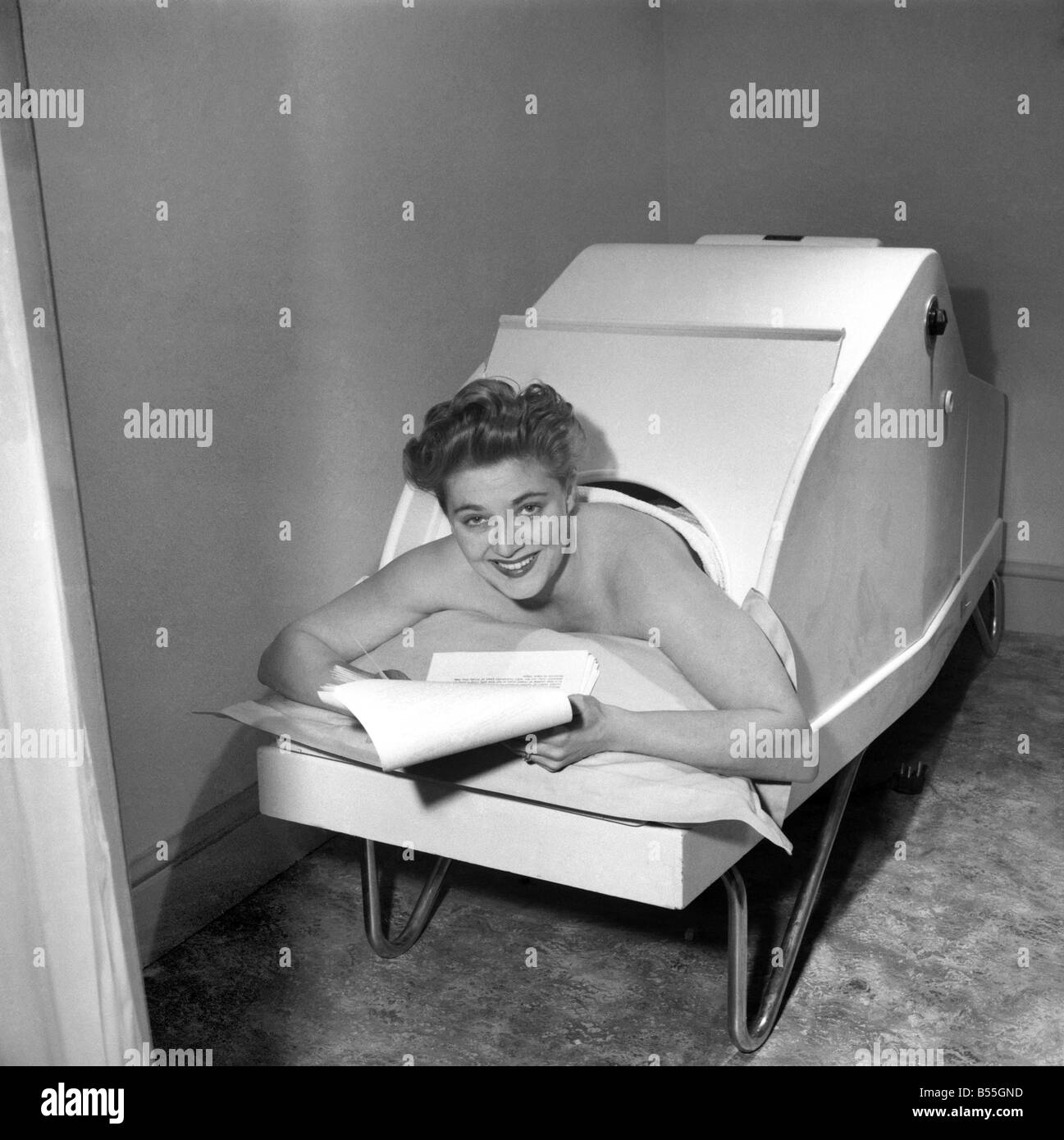 Actress Hy Hazel relaxes as she studies her part as Principal Boy in the Puss in Boots panto at the Manchester Palace in a new dry heat rheumatic bath. This bath, imported from Paris for the openign of a new beauty clinic in Manchester, is a refresher for the nervously exhausted. December 1953 ;D7370 Stock Photo