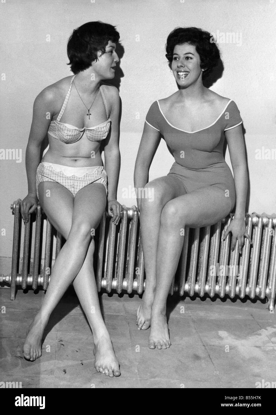 Strip Freeze. Models Verna Clarke and Thelma Drabble were happy to find this warm spot yesterday (14-1-59) at London's White House swimming pool. While everyone else was wrapping up against the icy weather Verna and Thelma had to strip off to parade at a swimsuit fashion show. Verena's bikini is in printed cotton lastex with a built - in bra and Thelma's is in cotton poplin. January 1959. P008710 Stock Photo