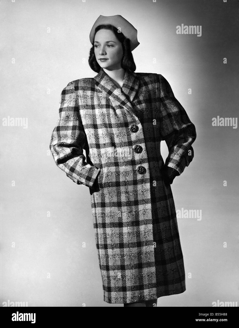 Fashion 1940's: Attractive swagger country coat by Meredith in large red, brown and green check, with large dolman sleeves and one pleat in back. P008738 Stock Photo