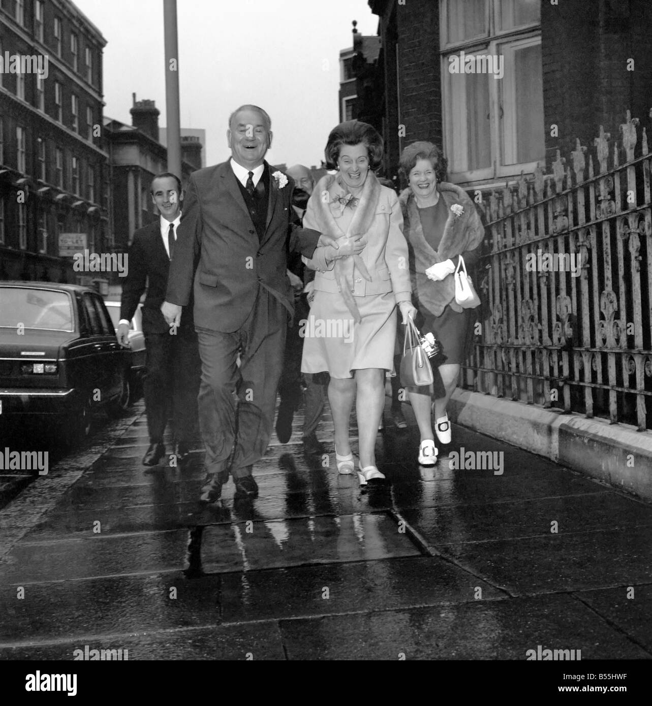 Married today at Caxton Hall Registrar Office was Lord Cooper, General Secretary of the Municipal and General Workers Union. His bride was childhood sweethart Joan Rogers, aged 58. The Bride and Groom running through the rain to a reception at a nearby Hotel. December 1969 Z11992 Stock Photo