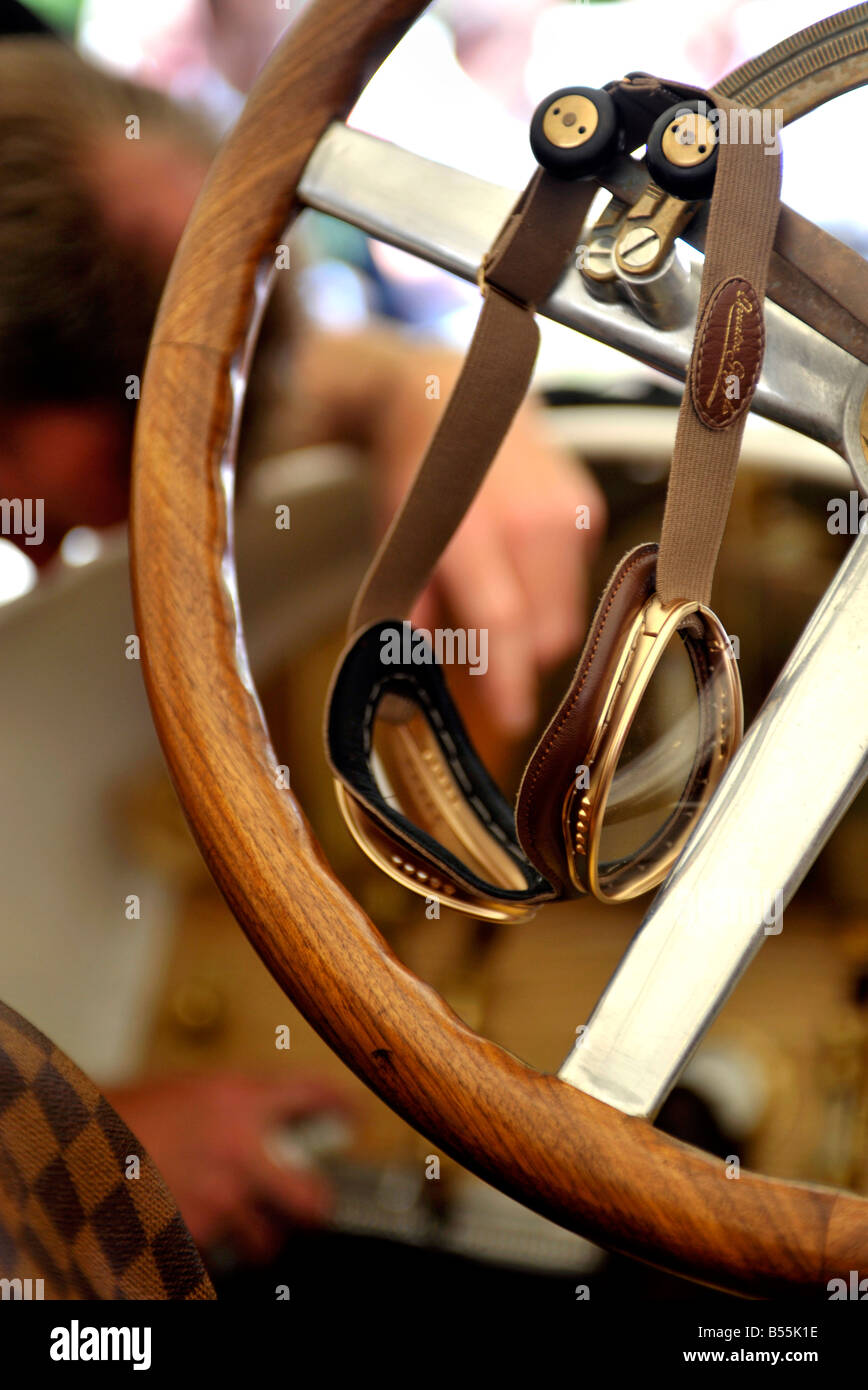 goggles hanging on historic racing car wood rimmed steering wheel at