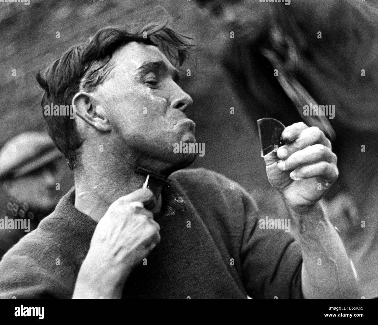 Character Studies. Man shaving using razor and broken piece of mirror&#13;&#10;P044416. Stock Photo