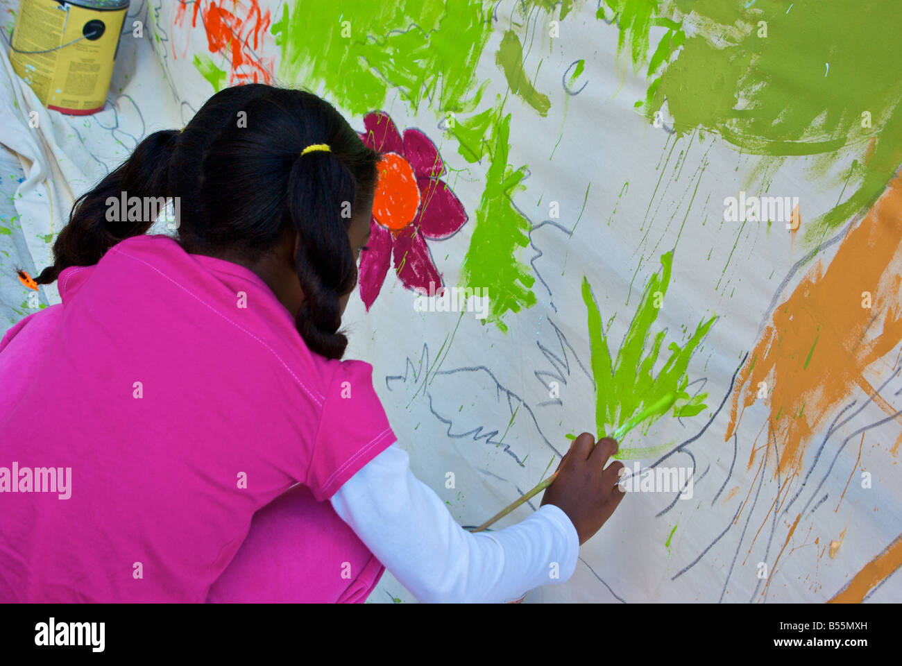 Young black Afro American girl painter adding her painting contribution to a mural at the Bayou City Art Festival Stock Photo