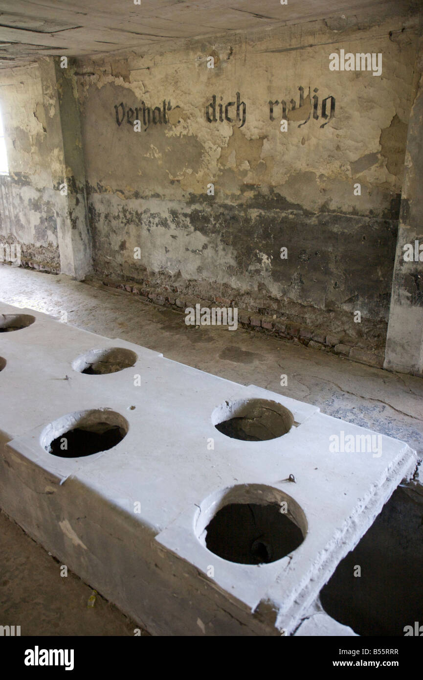 Mass toilet barrack with inscription 'Verhalte dich ruhig' in former concentration camp Auschwitz II (Birkenau) Stock Photo