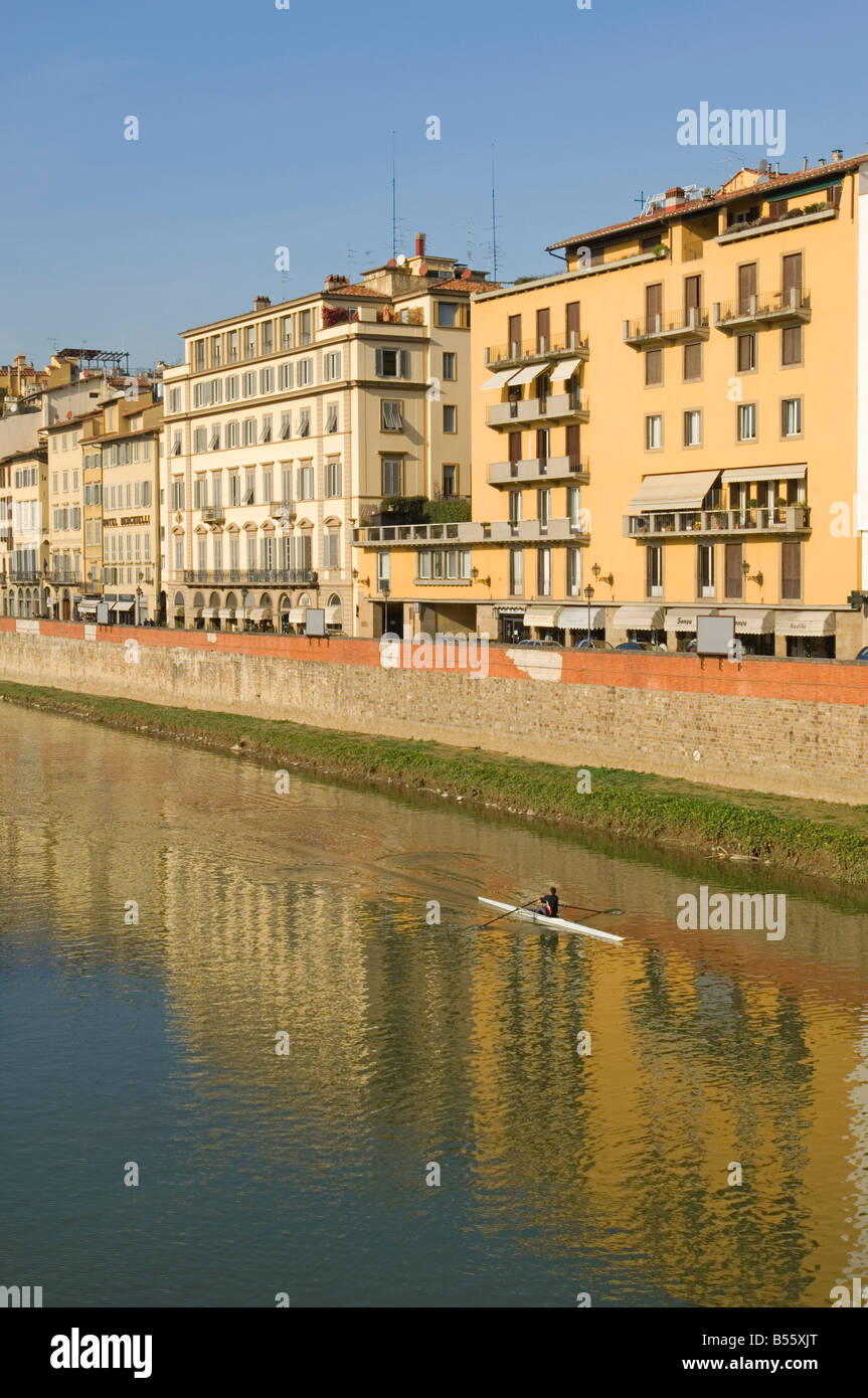 The buildings on Lungarno Degli Acciauoli in Florence reflected in the river Arno with a single rower on the water. Stock Photo