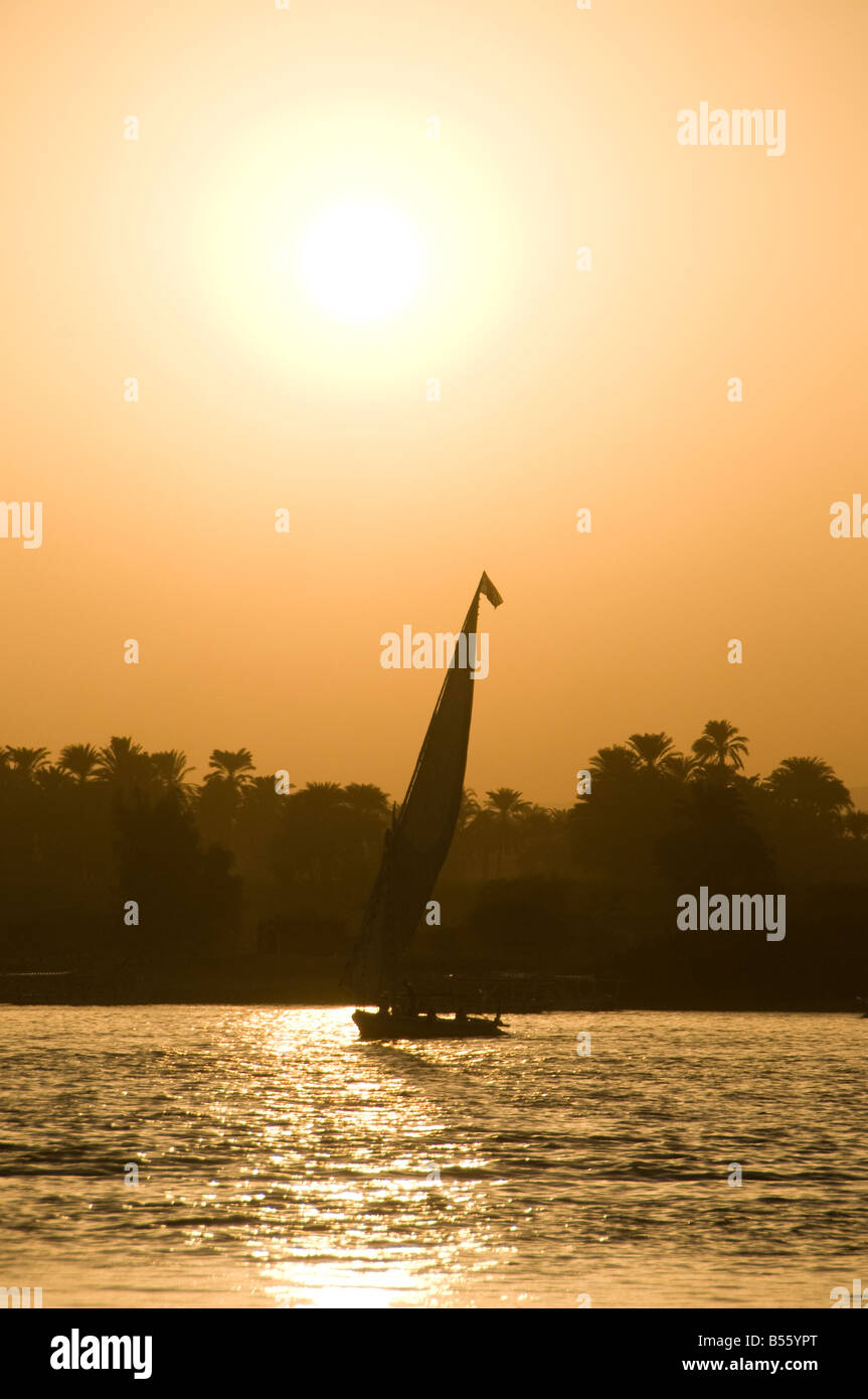 A silhouetted felucca traditional wooden sailing boat on the Nile river ...