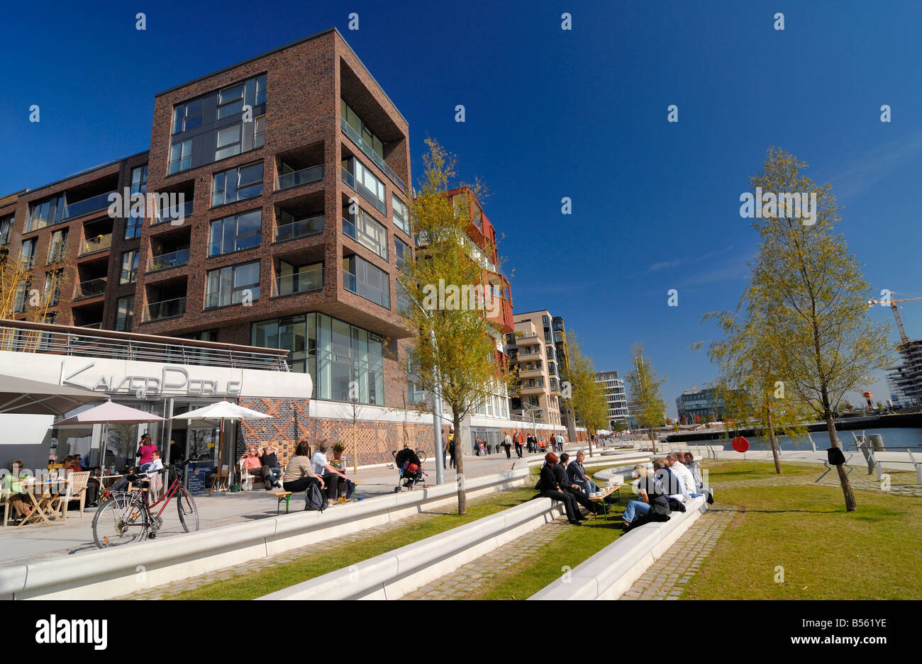 Modern building and the Café Kaiserperle with guests sitting along the Dalmannkaipromenade at the new Hafencity at the enlarged Stock Photo