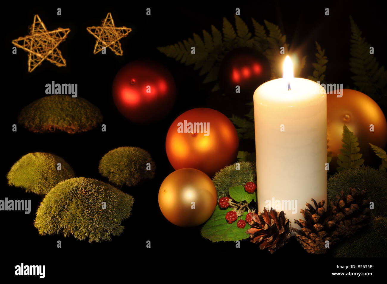 Christmas decoration: Christmas balls, burning white candle, berries, moss mounds and fern on black background. Stock Photo