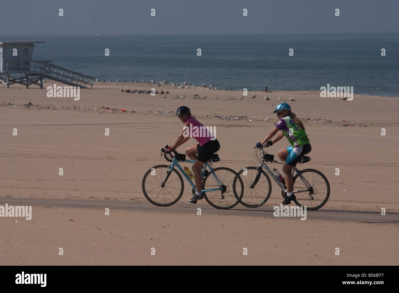 Two female cyclists on their morning ride along the beach Stock Photo