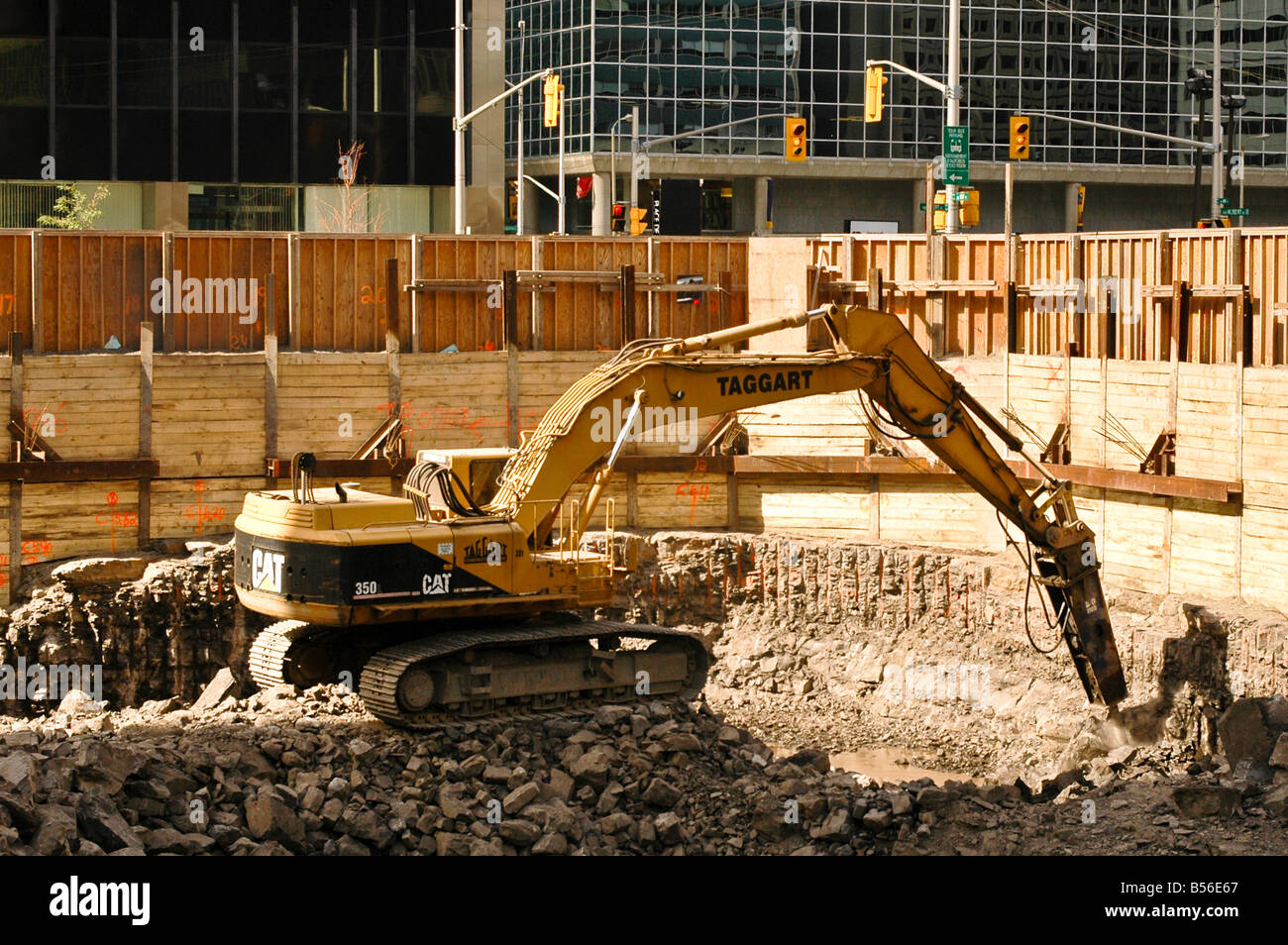 A large construction vehicle uses a jackhammer to break apart rocks in