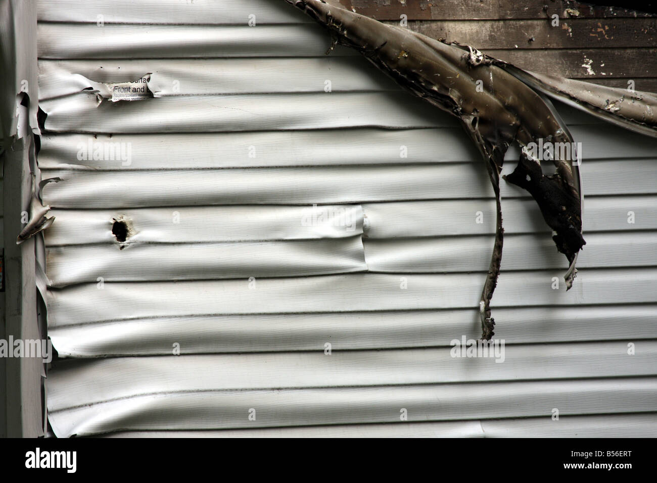 The vinyl siding of this garage has melted from the intense heat of the burning house next to it