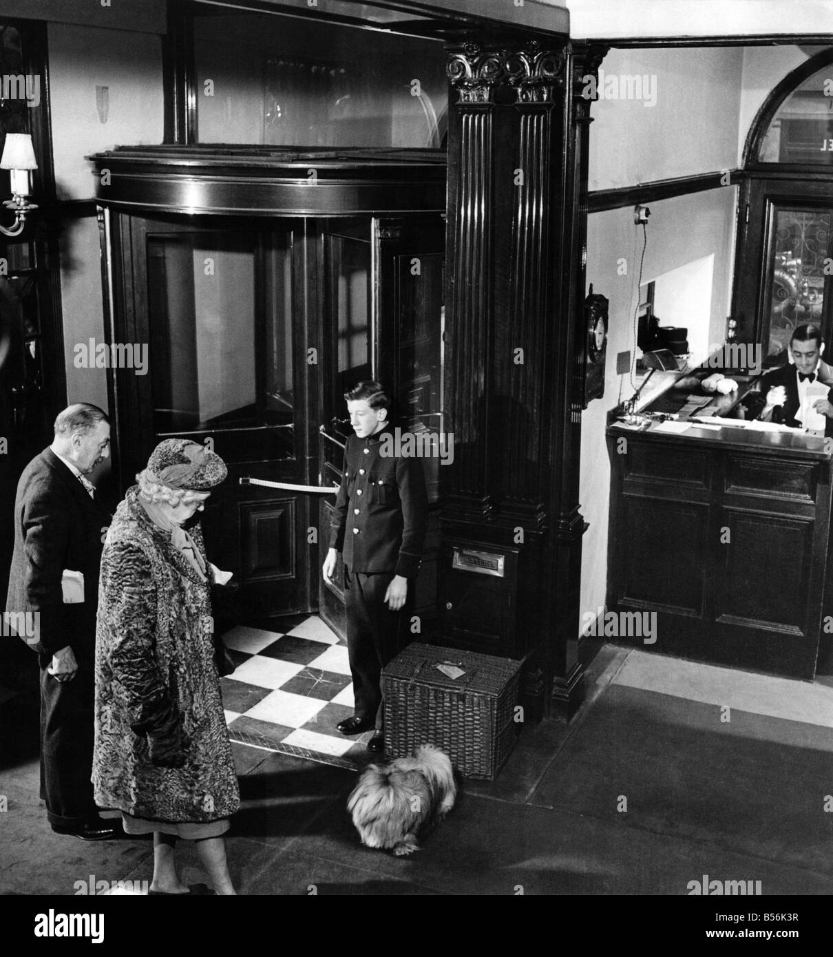 A typical lobby scene - the elderly lady and the Peke. The page's duty is to 'give it a run' first thing every morning. P009169 Stock Photo