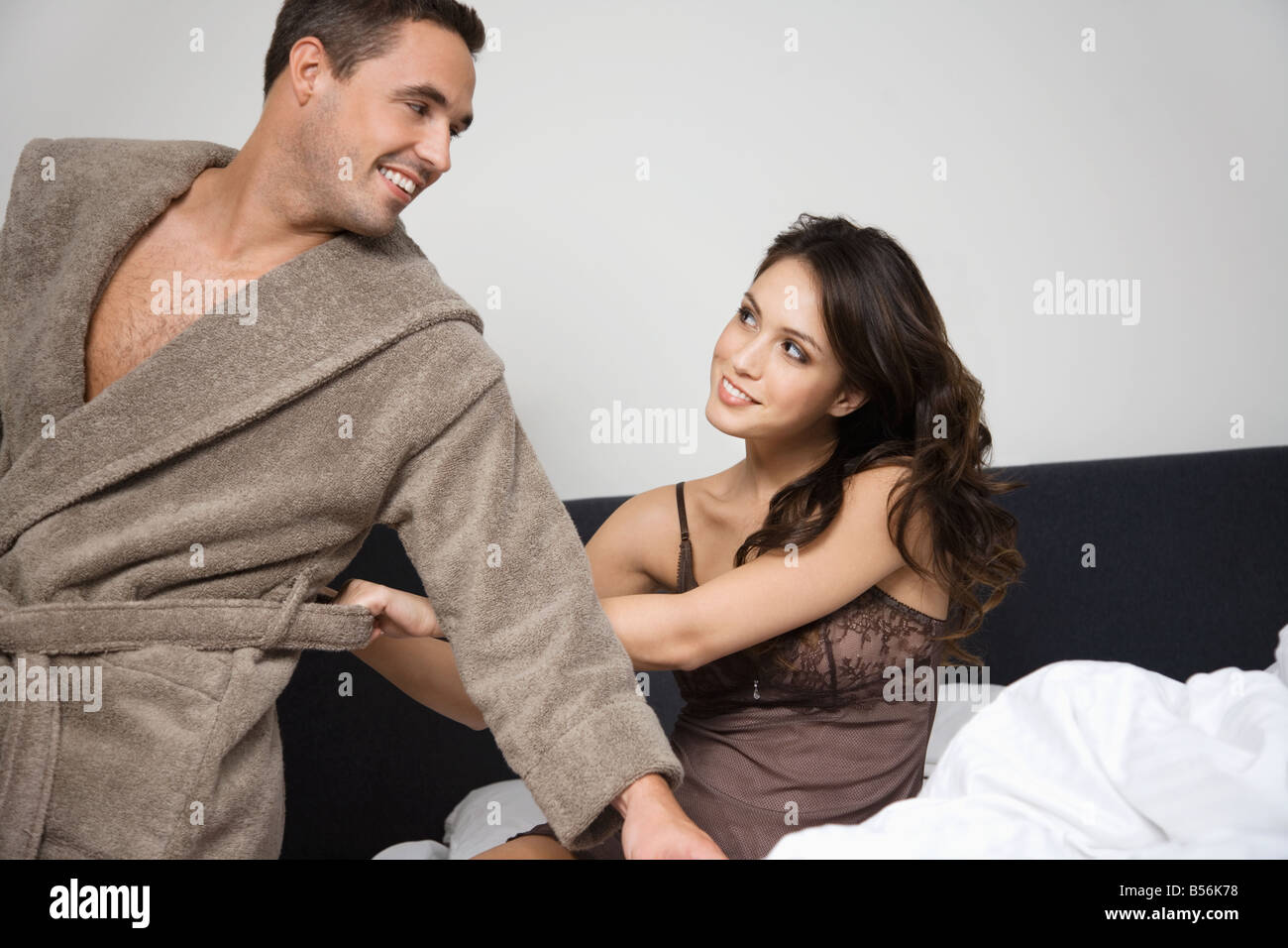 A woman pulling at a mans bathrobe Stock Photo
