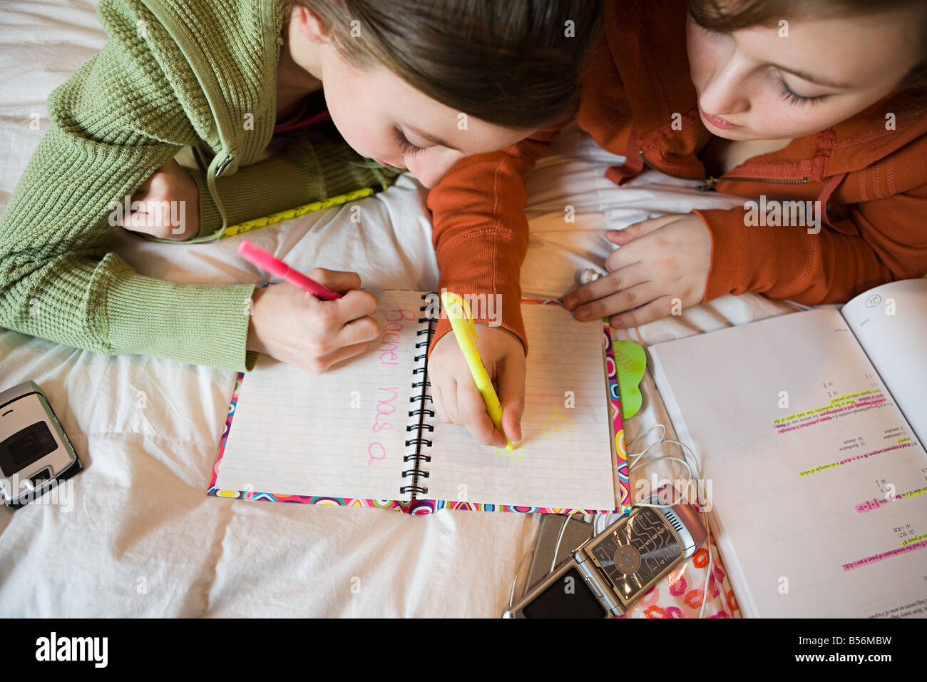 Two teenage girls writing in a book Stock Photo - Alamy