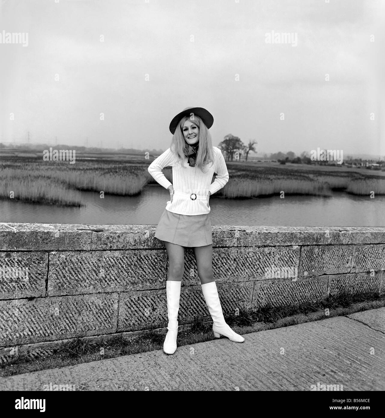 Young woman wearing a hat, mini skirt and knee high boots on the sea ...