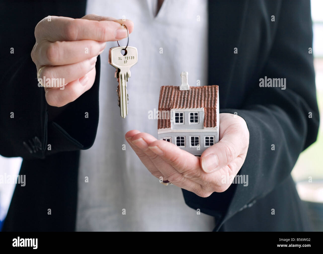 A business woman is holding a miniature house and keys Stock Photo - Alamy