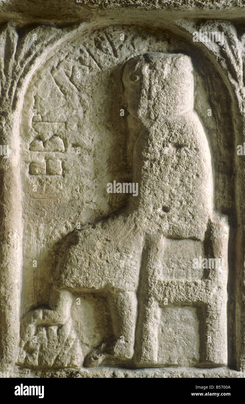 Burnham Deepdale Norman Font detail Month of February man wearing cowl warming feet by a fire labour of the month Romanesque Stock Photo
