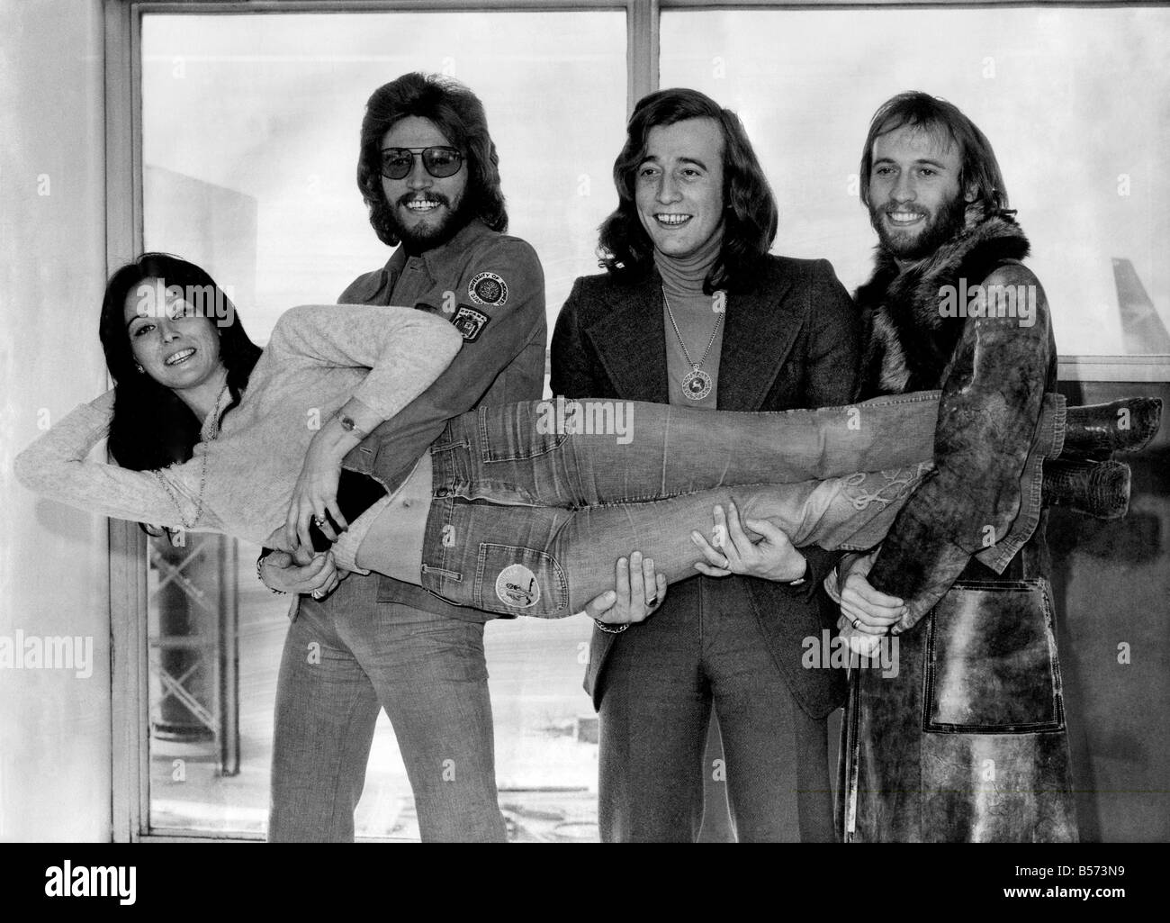 The Bee Gees pop group left Heathrow Airport today for Canada where they will be doing a singing tour, for five weeks (also in the U.S.A.). Barry, Robin and Maurice Gibb holding Linda who is the wife of Barry. February 1973 P003742 Stock Photo