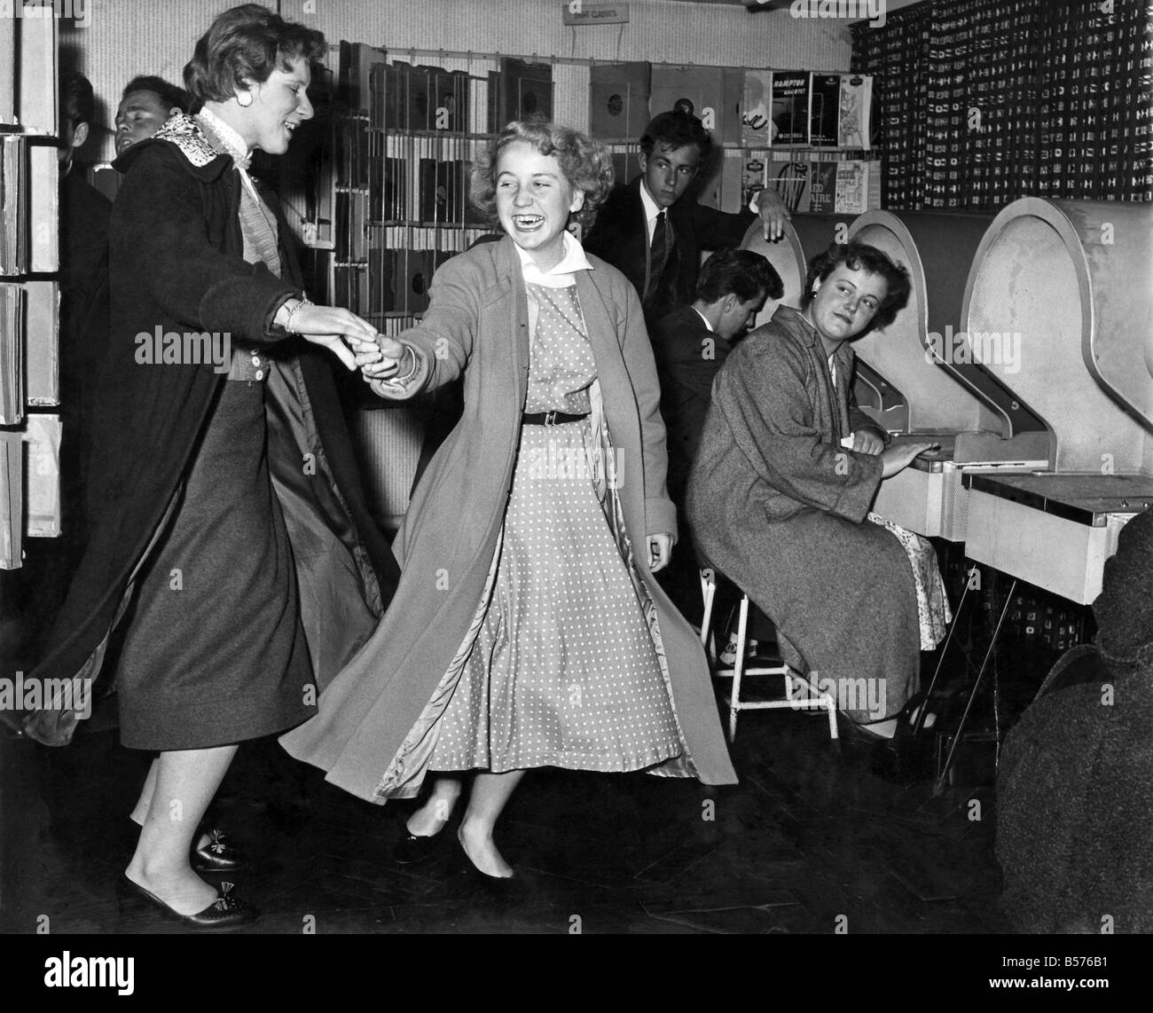 Youth Culture: Two girls dance whilst listening to the latest recordings at their local record shop. September 1956 P005401 Stock Photo