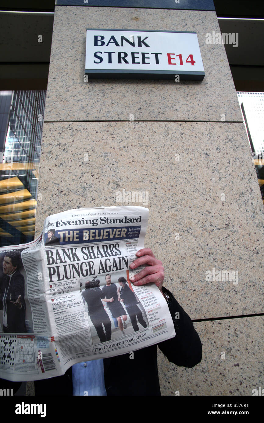 Worker in Bank Street Canary Wharf London reads gloomy news Stock Photo