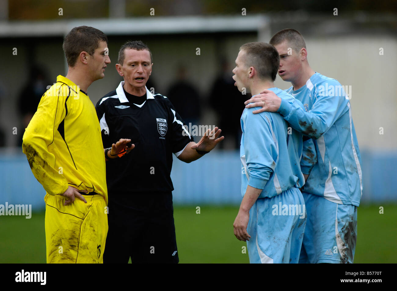 referee tries to calm down dispute between two opponents Stock Photo