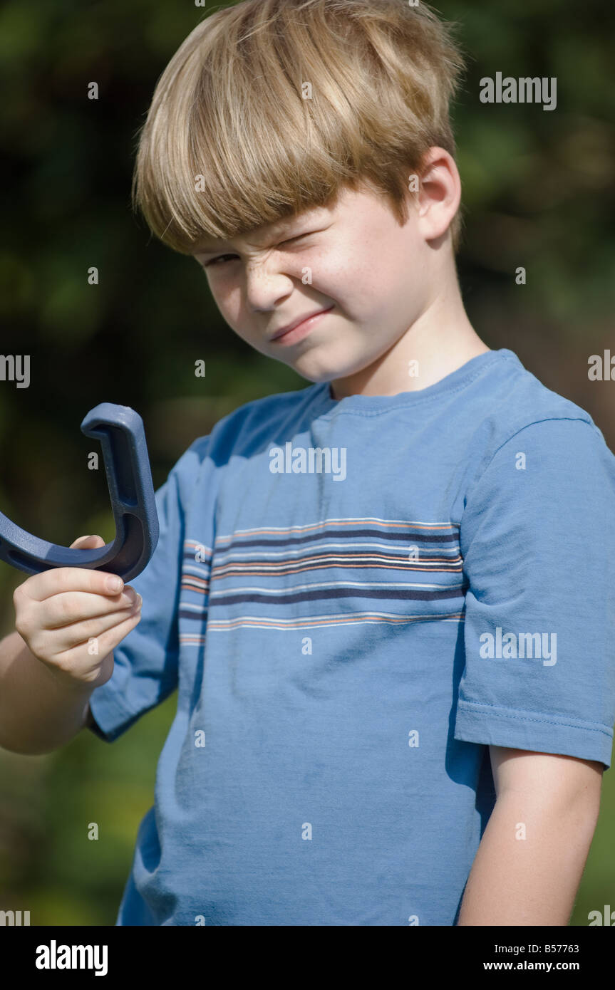 Young boy taking aim with horse shoe Stock Photo