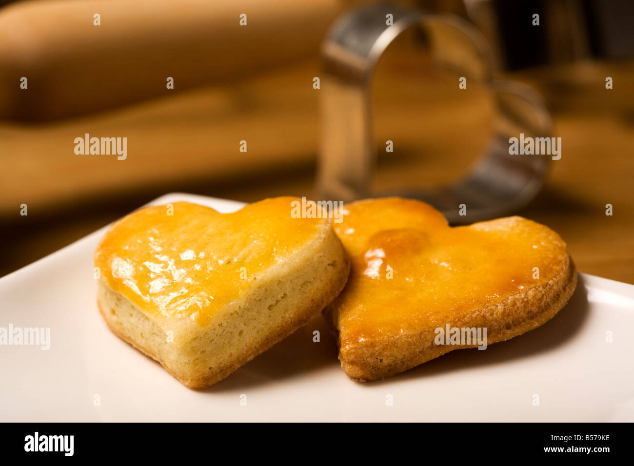 two heart shaped shortbread cookies, cookie cutter in background Stock