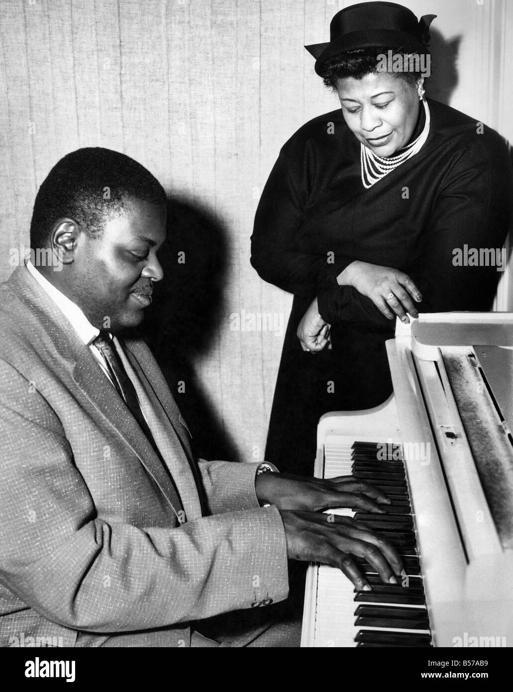 Jazz specialists arrive for tour of Britain. Ella Fitzgerald and Oscar Peterson, Jazz singer and piano specialists arrive in England for tour. They are to appear at the Albert Hall. As soon as they arrived at their hotel they began practising. Oscar Peterson at the piano with Ella Fitzgerald. February 1955 P007112 Stock Photo