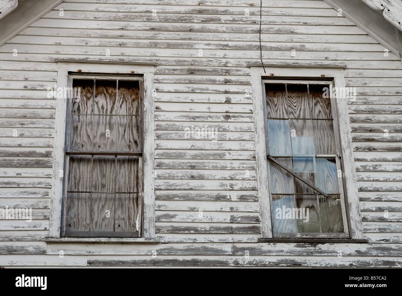 Boarded up windows on the side of an old run down house Stock Photo